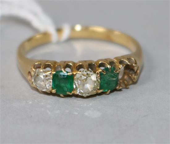 An early 20th century yellow metal and four (ex 5) stone diamond and green doublet half hoop ring, size S.